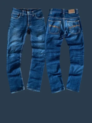 Blå jeans från Nudie Jeans, W28 L32 - Hej nu säljer ett par klassiska och snygga blå Nudie Jeans med snygga slitningar.Har använts med är i riktigt bra skick. Modellen har fem fickor och en normal passform. Är storlek 28 32. Priset är inte hugget i stenen än. Om du har några frågor eller funderingar så att de bara att skriva.