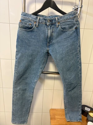 Levi's 512 blå raka jeans - Aldrig använda. Klassiska Levi's 512 jeans i ljusblå denim med raka ben och femficksmodell. Jeansen har knappgylf, bälteshällor och den ikoniska läderpatchen bak i midjan. Perfekta för en avslappnad och tidlös stil.      Nypris 1350kr