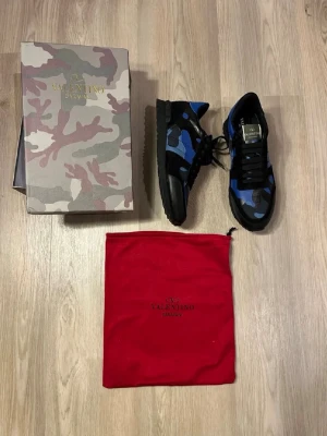Valentino rockrunners - Snygga sneakers från Valentino med blått och svart camo-mönster. Skorna har svarta snören, svarta detaljer och en klassisk låg siluett. Märkeslogga på plösen och insidan. Kommer med originalkartong och röd dustbag.