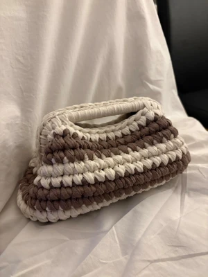 Clutch bag - Unik handgjord kuvertväska i virkad stil med breda ränder i krämvit och brun. Lagom stor väska där du får plats med mer än bara det nödvändigaste. Mått är ca: B:28 cm & H:16 cm. 