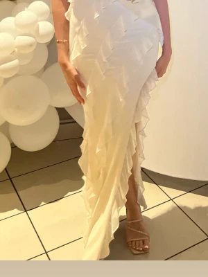 Oh polly. Vit långklänning med volangdetaljer   - Säljer min superfina Oh Polly "Nevali" Bandeau Ruffle Detail Maxi Dress i fargen Ivory Endast använd en gång och i jättefint skick. Perfekt till studentmottagning, studentfest, bal, bröllop eller andra fina tillfällen. Ordinarie pris: $80.00 Mitt pris: 500 kr Storlek: UK 6 / US 4, motsvarar ungefär XS / EU 34.