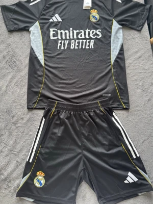 Real Madrid set - Svart Real Madrid set med shorts och T-shirts. Shortsen var fickor med dragkedja och både tröjan och shortsen är bra passform. Skriv vid frågor!