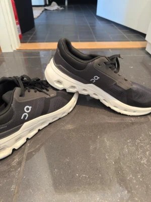 Svarta On Cloud sneakers - Snygga svarta On Cloud sneakers med vit chunky sula och ventilerande meshmaterial. Skorna har svarta snören, diskret logga på sidan och modern design som passar perfekt till streetwear. Lätta och bekväma för dig som gillar att röra på dig. Använda under 5 gånger!