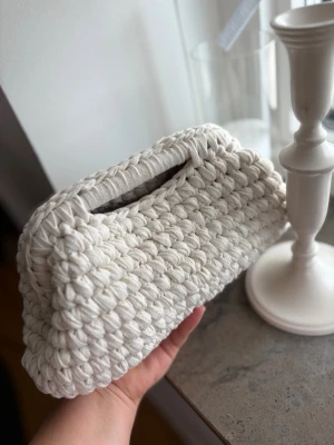 Clutch bag  - Superfin handvirkad clutch i färgen krämvit. Väskan har en unik och trendig look, perfekt för att lyfta din outfit. Tillverkad i återvunnet material. Mått är ca: B:28&H:16