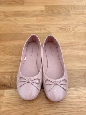 Ljusa rosa ballerinaskor med rosett💕 - Snygga ljusrosa ballerinaskor från Anna Field med glansig finish och söt rosettdetalj framtill. Skorna har rund tå och klassisk ballerinamodell. Materialet är syntet och insidan är mjukt fodrad för extra komfort. Jag säljer dessa för att de vart för små för mig, annars har jag bara haft på mig dessa en gång💕