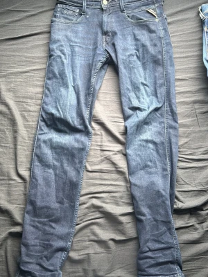Replay anbass 28/30  - Snygga blå slim fit jeans från Replay med klassisk femficksdesign och dragkedja. Jeansen har en något tvättad look och raka ben. Tillverkade i mjukt denimtyg som ger en bekväm känsla och passar perfekt till en avslappnad stil.