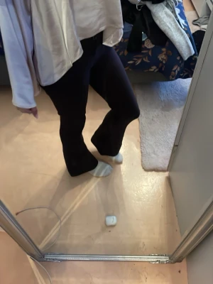 Svarta utsvängda kostym byxor - Säljer ett par svarta kostymbyxor med utsvängda ben. De har hög midja och sitter tight över låren för att sedan bli vidare nedtill. De har ett par snygga fickor med knapp. Perfekta för dig som gillar en trendig och bekväm stil. Materialet är stretchigt och mjukt, vilket gör dem sköna att bära hela dagen. Köpta från Gina i vanlig längd. Ser helt nya ut men har knopp på rumpan som kan gå bort.