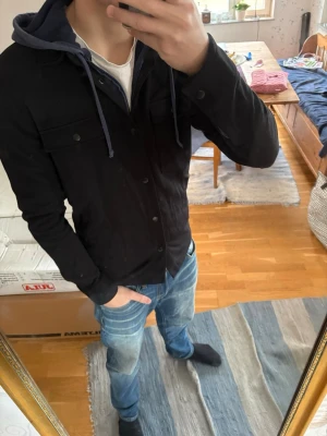Svart overshirt - Stilren svart overshirt med knappar framtill . Overshirten har en rak passform och är tillverkad i ett mjukt, lite tjockare material som passar perfekt som lager över en hoodie eller t-shirt. Fortfarande väldigt bra skick utan defekter. Nypris 750 kr, mitt pris 250 kr 