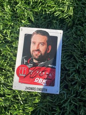 Ishockeykort Jhonas Enroth Örebro - Samlarobjekt! Ett ishockeykort med Jhonas Enroth från Örebro Hockey. Kortet har en färgbild på spelaren i röd och svart matchtröja, klubbens logga och spelarens namn tryckt längst ner. Kortet är signerat med svart tusch.