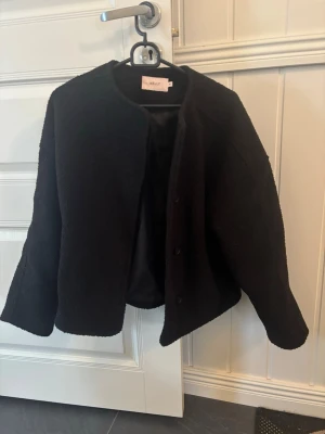 Svart cardiganjacka från Nelly - Superfin cardiganjacka från Nelly med knäppning framtill. Jackan har en rak, boxig passform och är tillverkad i ett mjukt material. Nypris 399kr.