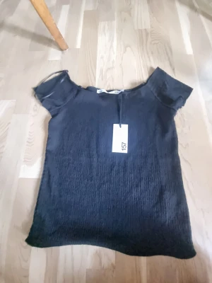 Svart ribbad topp från lager 157 - Säljer en svart ribbad topp från lager 157 i storlek S. Den offshoulder men går att ha den på axlarna. Prislappen är kvar