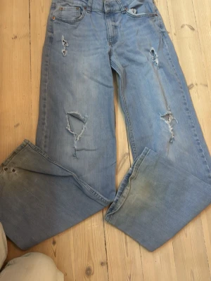 Nelly baggy jeans med hål - Säljer ett par ljusblå jeans från Nelly med slitningar och hål på benen för en trendig look. Jeansen har raka ben, klassisk femficksmodell och är gjorda i denim. Perfekta för dig som gillar en avslappnad och cool stil.