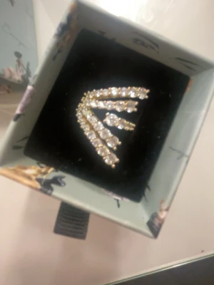 Guldring  med kristaller från Ioaku - Pris kan diskuteras, skriv gärna!💓Unik ring  från Ioaku i guldton med tre rader av gnistrande klara kristaller. Ringen  har en modern, v-formad design som ger en cool och trendig look. Perfekt accessoar för dig som vill sticka ut och addera lite extra bling till din stil.