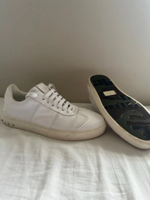 Valentino flycrew - Snygga vita sneakers från Valentino Garavani i läder med klassisk låg siluett. Skorna har vita snören, diskreta sömmar och logga på plösen. Yttersulan är vit med detaljer och undersidan har ett svart mönster. Perfekta för en clean och stilren look. Storleken är 44 men den känns liten enligt mig passar förmodligen 43 bättre.