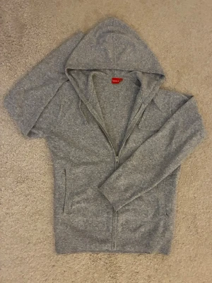 Grå hoodie med dragkedja från RYVLS - Klassisk grå hoodie från RYVLS med dragkedja framtill och huva. Tillverkad i mjuk bomullsmix och har långa ärmar, Perfekt för en chill och avslappnad stil. Hoodien i storlek 164cm men passar till ca170-175cm och är i perfekt skick✅ Fraktar inom en dag✅ Priset är inte hugget i sten🙂