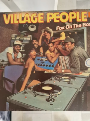 Village People - Fox On The Box LP - LP-skiva med Village People, albumet 'Fox On The Box'. Omslaget har färgstark design med gruppen i en studio och på gatan. Skivan är i klassiskt svart vinyl och omslaget är gjort av kartong med tryckt text och bilder. Inga repor.