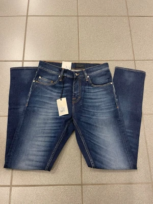 Mörkblå tiger of Sweden jeans  - Snygga mörkblå jeans med tvättade detaljer och klassisk femficksmodell. Jeansen har kontrastsömmar och en patch i brunt vid linningen bak. Rak passform och tillverkade i denim med stretch för extra komfort. Från tiger of Sweden 