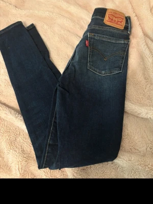 Levi's 710 Super Skinny jeans blå - Säljer ett par mörkblå Levi's 710 Super Skinny jeans i storlek 24. Jeansen har klassisk femficksdesign, smal passform och är tillverkade i stretchigt denim för en bekväm känsla.
