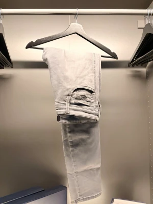 Replay - Säljer ett par ljusgrå jeans med rak passform och klassiska fem fickor. Jeansen har en enkel design utan synliga loggor och är tillverkade i ett mjukt denimtyg. Perfekta för en clean och stilren look.