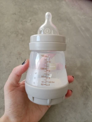Grå nappflaska från MAM 160 ml - Säljer en söt nappflaska från MAM i grått med genomskinlig kropp och motiv av en liten kanin. Flaskan rymmer 160 ml och har tydliga måttangivelser på sidan. Tillverkad i plast med silikonnappp och bred öppning för enkel påfyllning.