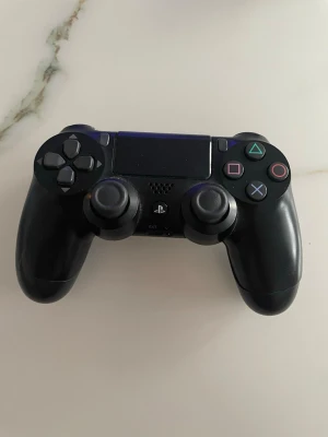 Svart DualShock 4 handkontroll PS4 - Säljer en svart DualShock 4 handkontroll till PlayStation 4 från Sony. Handkontrollen har klassisk layout med två analoga spakar, styrkors, touchpad och de ikoniska PlayStation-knapparna i färg. Tillverkad i plast med ergonomisk form för skönt grepp.