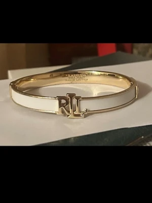 Ralph lauren armband  - Säljer denna snygga Ralph Lauren armband i färg guld-coulured/white, riktig fin armband för kvinnor, armbandet är knappt använd, fick den i födelsedagspresent. Ny pris på denna är 929kr på zalando. Pris kan diskuteras!!  Omkrets: 17 cm i storlek One Size Armbandsbredd: 0.7 cm i storlek One Size