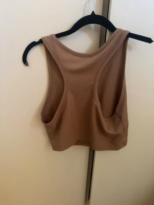Beige ribbad croppad linnetopp - Säljer en beige croppad linnetopp från Zara. Toppen är ribbad och har breda axelband samt rund halsringning. Perfekt för att styla med höga jeans eller kjol. Enkel och stilren design som passar till många olika looks.
