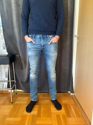Blå slim fit jeans med slitningar - Snygga blå slim fit jeans med slitningar och tvättade detaljer från Replay.