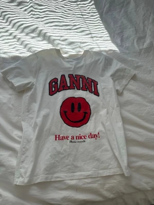 Vit Ganni t-shirt med smileytryck - Vit t-shirt från Ganni med rött smileytryck.