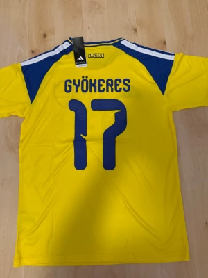 Gyökeres #17 – Sverige Hemma (storlek M) - Gyökeres #17-tryck. Sverige Hemma (gul). Storlek M. Helt ny och aldrig använd. Skickas snabbt 🚚💨  Mått (M): Halvt bröstmått 53 cm • Längd 74 cm • Ärmbredd 23 cm • Axelbredd 44 cm • Ärmlängd 40 cm • Manschett 19 cm.  🔥 Fan Edition – normal passform. 🇸🇪 Sverige landslag.  📩 Frågor eller prisförslag? Skicka gärna ett meddelande! 🛍 Bundle-rabatt upp till 20% 💰 📦 Skickas samma eller nästa dag 🌟