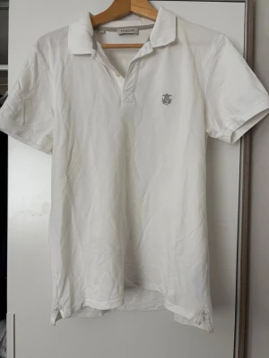 Vintage piké från Selected Homme - Klassisk vit pikétröja från Selected Homme med korta ärmar och krage. Tröjan har en liten broderad logga på bröstet och är tillverkad i mjuk bomull. Perfekt för en clean och stilren look.