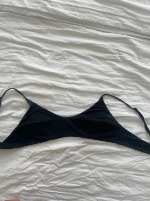 Svart minimalistisk bikinitopp - En svart bikinitopp med tunna, justerbara axelband och enkel, slät design.