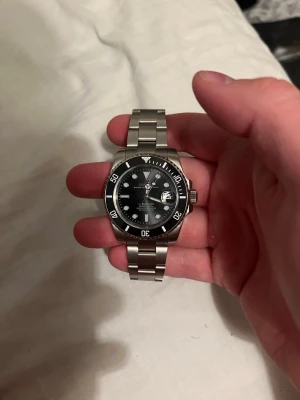 Seiko mod Submariner - Riktigt snygg och sprillans ny seiko mod submariner. Klassisk och stilren design med svart tavla och svart bezel. 44mm stor med äkta seiko nh35 automatiskt urverk med runt 40 timmars kraft reserv. Den har datum visare, vridbar bezel, oyster armband med 3 extra länkar och glasad baksida så du kan se urverket. Har en väldigt skön tyngd. Kan mötas i Nacka/stockholm stad eller närliggande områden om det är intressant.