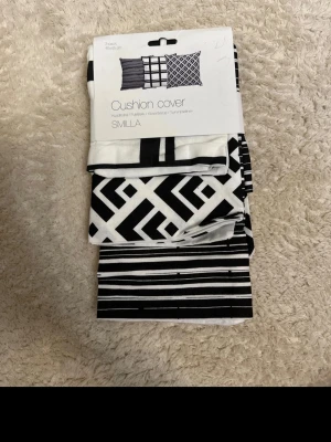 Svartvita kuddfodral SMILLA 3-pack - Säljer ett 3-pack kuddfodral från SMILLA i svartvitt med olika grafiska mönster. Fodralen är tillverkade i tyg och har moderna, stilrena tryck som passar till många inredningsstilar. Perfekt för att ge soffan eller sängen en ny look.