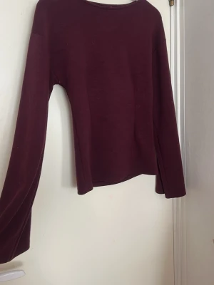 Vinröd långärmad topp från Nelly - En enkel och stilren vinröd långärmad topp från Nelly. Modellen har rund halsringning och är tillverkad i ett mjukt material som sitter bekvämt på kroppen. Perfekt att matcha med jeans eller kjol för en clean look.