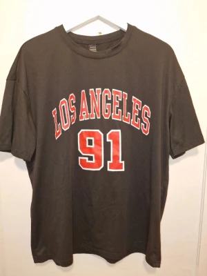 Svart Los Angeles 91 t-shirt - Cool svart t-shirt med 'Los Angeles' tryck framtill. Avslappnad passform, perfekt till jeans. Oversize passform.