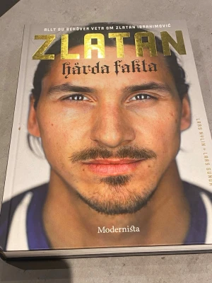 Allt du behöver veta om Zlatan Ibrahimović - En bok om Zlatan Ibrahimović skriven av Lars Nylin och Lars Sundh. Omslaget är vitt med ett porträtt av Zlatan och guldfärgad text. Inbunden bok med många bilder och intressant fakta om Zlatans liv och karriär. Perfekt för dig som gillar fotboll och biografier.