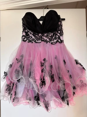 Balklänning Sherri Hill - Säljer en vacker Sherri Hill-klänning i rosa och svart med tyllkjol och fina fjärilsdetaljer.   Vintage modell. Ursprungligen storlek M men insydd för att passa ca XS/S (US 2/0). Kan sys ut igen om man önskar större storlek. Använd men i fint skick.