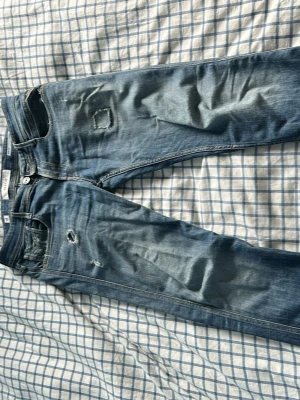 Blå replay anbass med slitningar - Säljer ett par blå replay anabss med slitningar. Str W29 L32. Har lagts till en lapp på höger ben som man kan se men de har en härlig passform och passar till det mesta. 