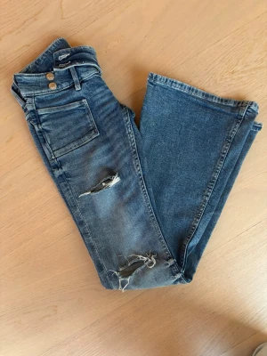 Snygga lowwaist jeans med hål - Säljer ett par jättesnygga trendiga jeans med hål ifrån Gina Tricot. Storlek xxs 14+ men skulle säga passar runt xs också. Pris kan diskuteras innerbenslängd: 80 