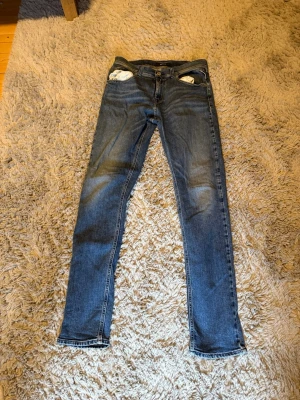 Blå skinny jeans från Replay - Säljer ett par klassiska blå skinny jeans från Replay  med fem fickor och snygga kontrastsömmar. Jeansen har normal midja och är tillverkade i stretchigt denim för en bekväm passform. Perfekta till en avslappnad stil.