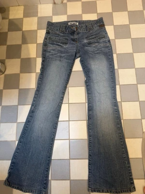 Blå bootcut jean - Säljer ett par blå bootcut jeans med ljus tvätt. Jeansen har coola fickor och vida fickor. Köpta second hand men aldrig använt själv!