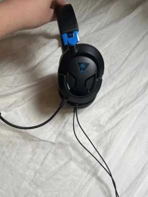 Gaming headset av PlayStation - Funkar både till pc och playstation.   Säljer ett Turtle Beach gamingheadset med sladd, svart och blå design. Stora, vadderade kåpor och justerbar bygel för skön passform. Inbyggd mikrofon och Turtle Beach-logga på sidorna. Perfekt för gaming och voice chat.