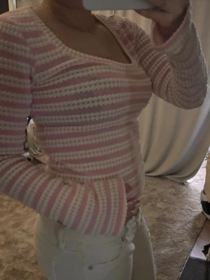 Rosa och vit stickad topp - Söt stickad topp i rosa och vitt med horisontella ränder och strukturmönster. Rundad, bred ringning och halvlånga ärmar. Perfekt för dig som gillar en mjuk och retroinspirerad look. Materialet känns mjukt och stretchigt.