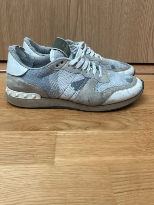 Valentino skor  - Snygga sneakers från Valentino i grått och vitt med mesh och mockadetaljer. Skorna har vita snören, gröna detaljer på.