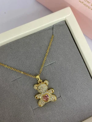 Guldigt halsband med nalleberlock - Sött halsband med en guldpläterad kedja och en gnistrande nalleberlock täckt av små klara stenar. Nallen har ett hjärta i rosa sten på magen som ger en extra gullig touch. Ej använd utan kommer från min small business.