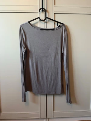 Grå långärmad topp från 157 - En enkel och stilren grå långärmad topp från 157. Tillverkad i mjuk och stretchig viskosblandning med rund halsringning. Perfekt basplagg att matcha med olika outfits.