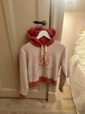 Saint Laurent rosa hoodie med tryck - Säljer en hoodie från Saint Laurent i ljusrosa och mörkrosa toner med tryck framtill. Hoodien har huva med dragsko och ribbade muddar vid ärmslut och midja. Perfekt för en avslappnad och trendig look.