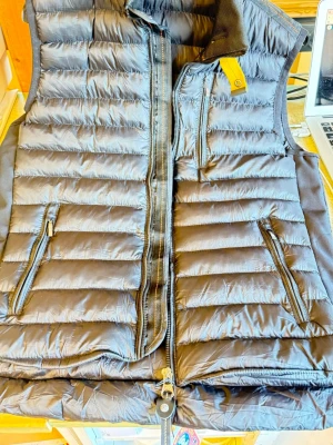 Svart dunväst från Parajumpers - Snygg svart dunväst från PJ med horisontella sömmar, två dragkedjefickor fram och en bröstficka. Västen har hög krage och orange detaljer på insidan. Perfekt för lager-på-lager-stil.