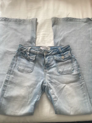 Ljusblåa lowwaist bootcut jeans  - Säljer ett par ljusblåa jeans från Queen hearts med låg midja och bootcut. Jeansen har coola  fickor fram. Perfekta för en avslappnad och trendig look.